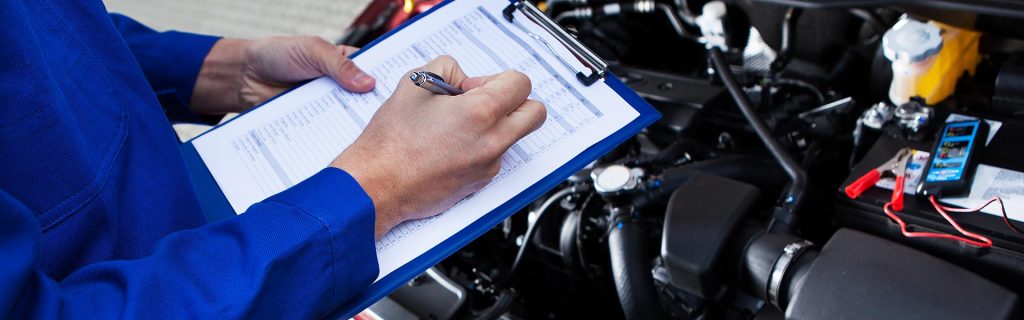 Technician performing a GMC Service inspection and maintenance check under the hood of a vehicle.